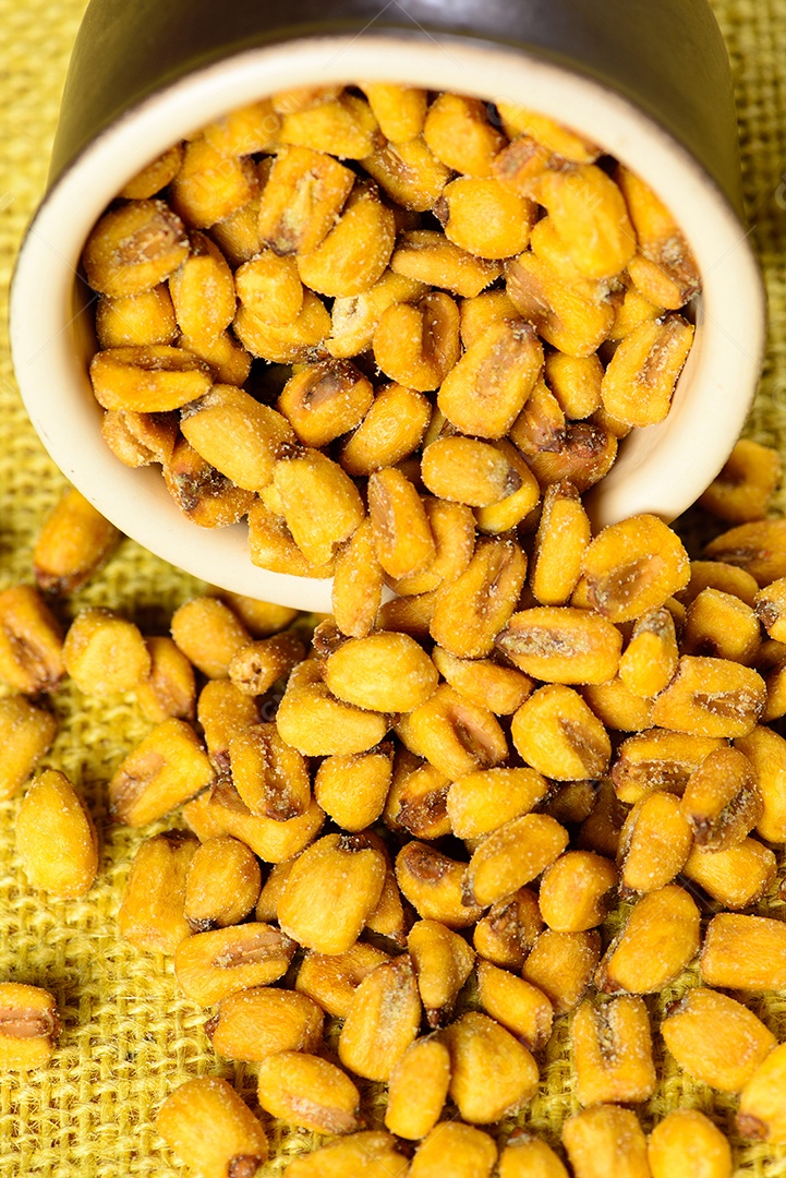 Milho torrado e salgado em pote de cerâmica sobre juta amarela