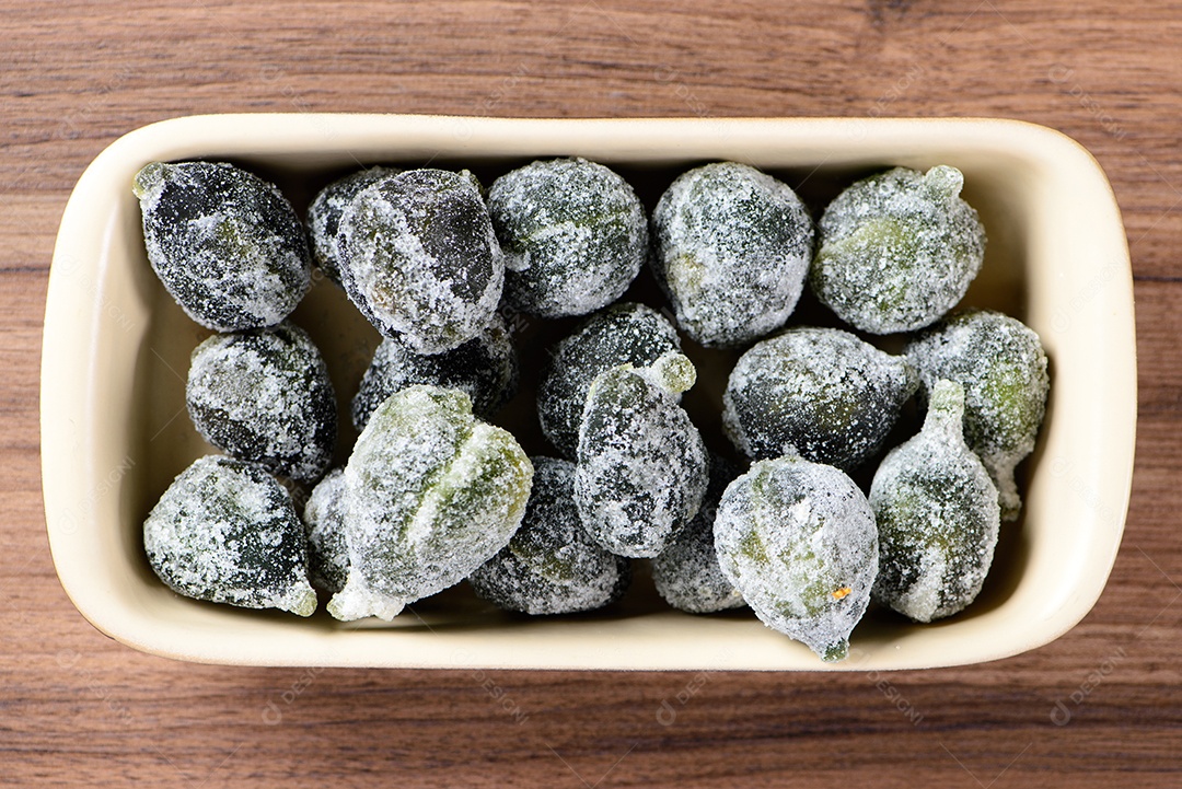 Figo cristalizado em recipiente de cerâmica em madeira marrom