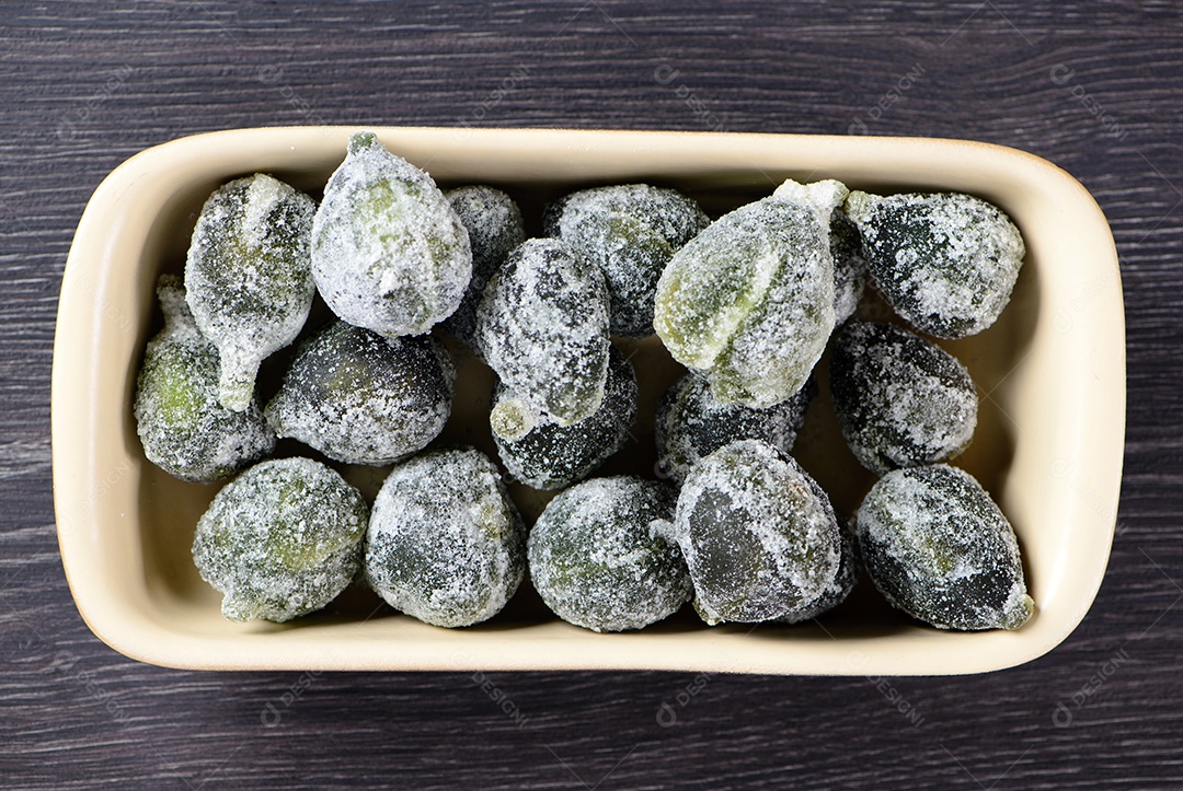 Figo cristalizado em recipiente de cerâmica em madeira escura