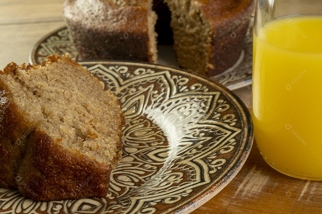 Bolo de banana e suco de laranja na mesa de madeira