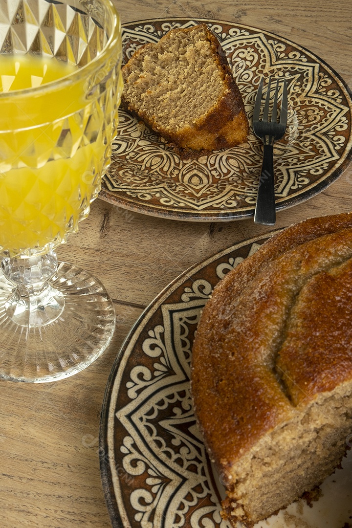 Bolo de banana e suco de laranja na mesa de madeira