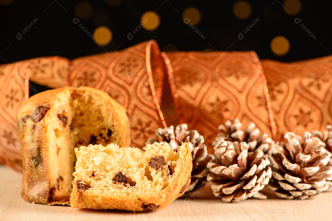 Pequeno panetone com uma fatia ao lado de pinhas e decorativo