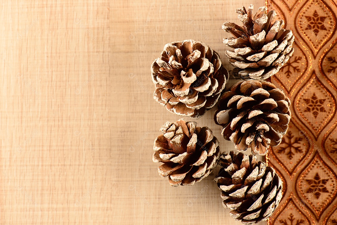 Pequeno panetone com uma fatia ao lado de pinhas e decorativo