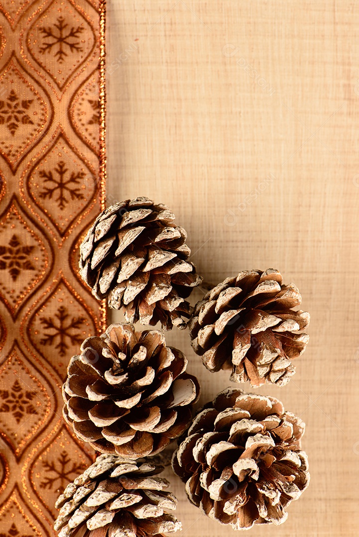 Algumas pinhas sobre fita marrom decorativa e madeira