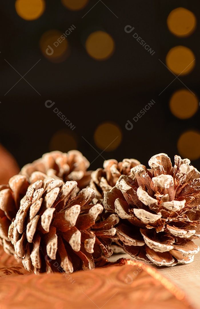 Algumas pinhas sobre fita marrom decorativa e madeira