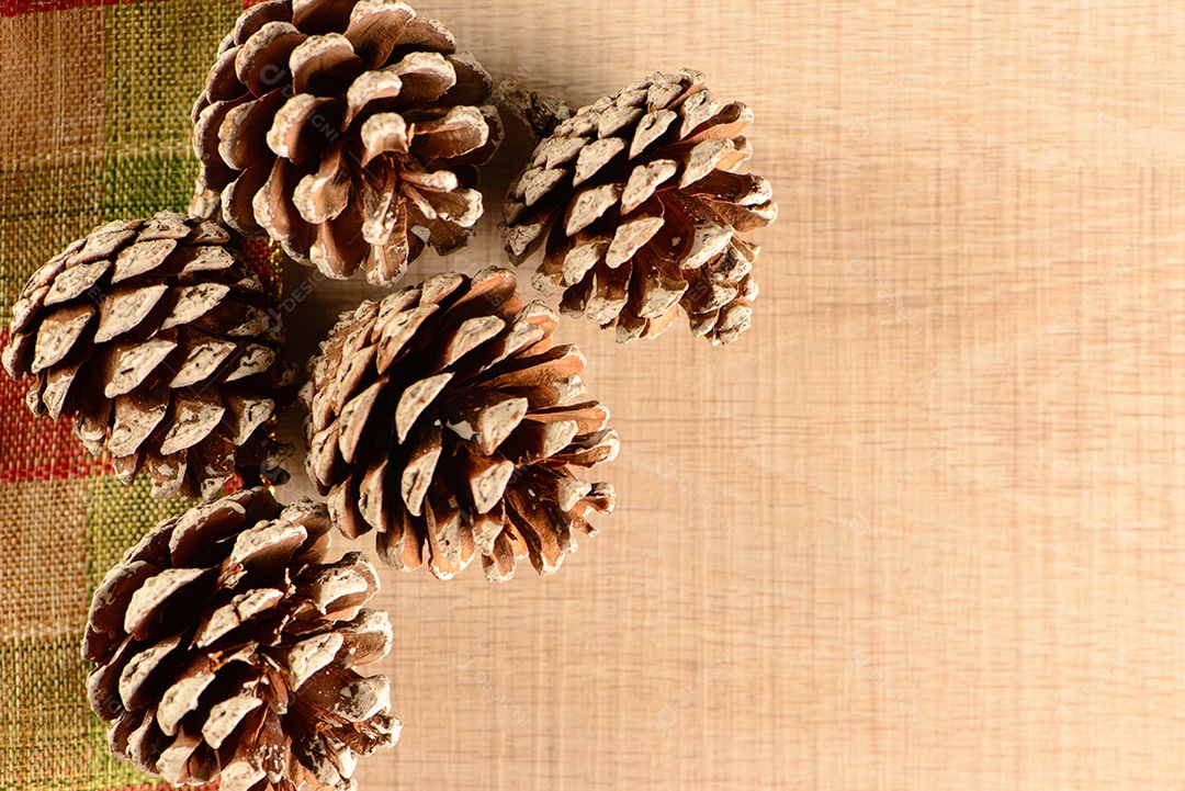 Algumas pinhas sobre fita quadriculada decorativa e madeira