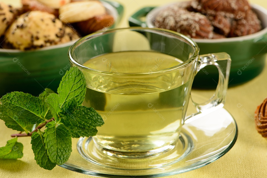 Chá de menta em copo transparente com biscoitos doces ao redor
