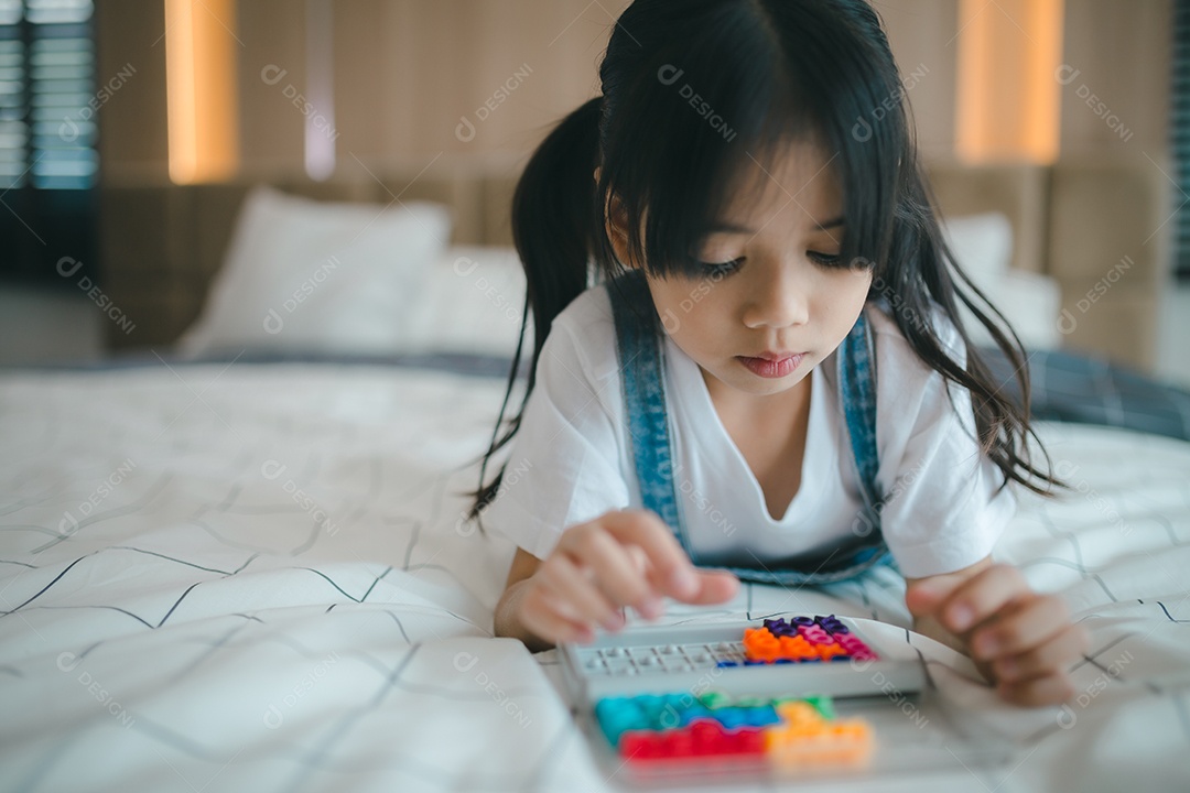 Criança asiática brincando com brinquedos na cama no quarto.