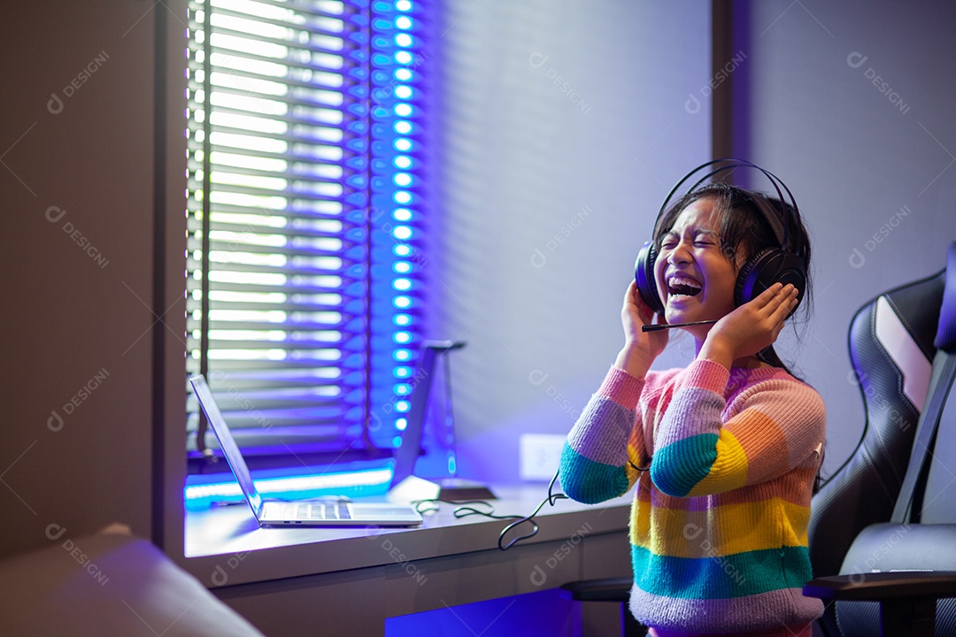 Garota asiática atraente ouvindo música com fones de ouvido no quarto.