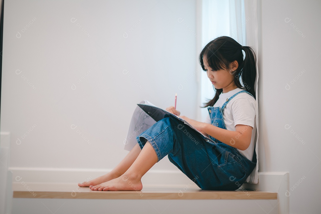 Menina asiática desenhando com lápis nas escadas em casa.