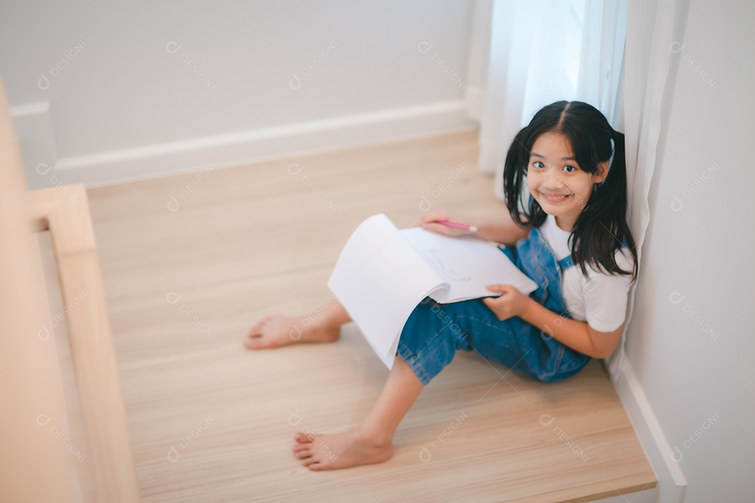 Menina asiática desenhando com lápis nas escadas em casa.