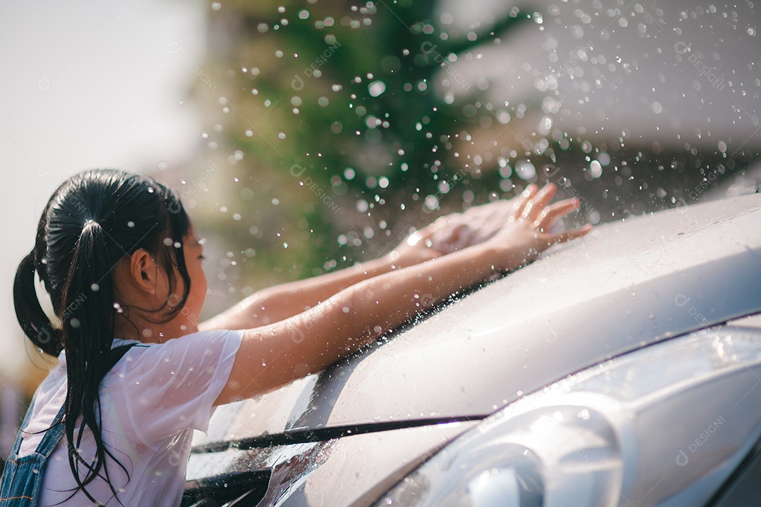 Irmãs asiáticas lavam seus carros e se divertem brincando dentro de casa em um dia quente de verão.