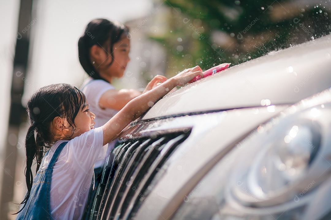 Irmãs asiáticas lavam seus carros e se divertem brincando dentro de casa em um dia quente de verão.