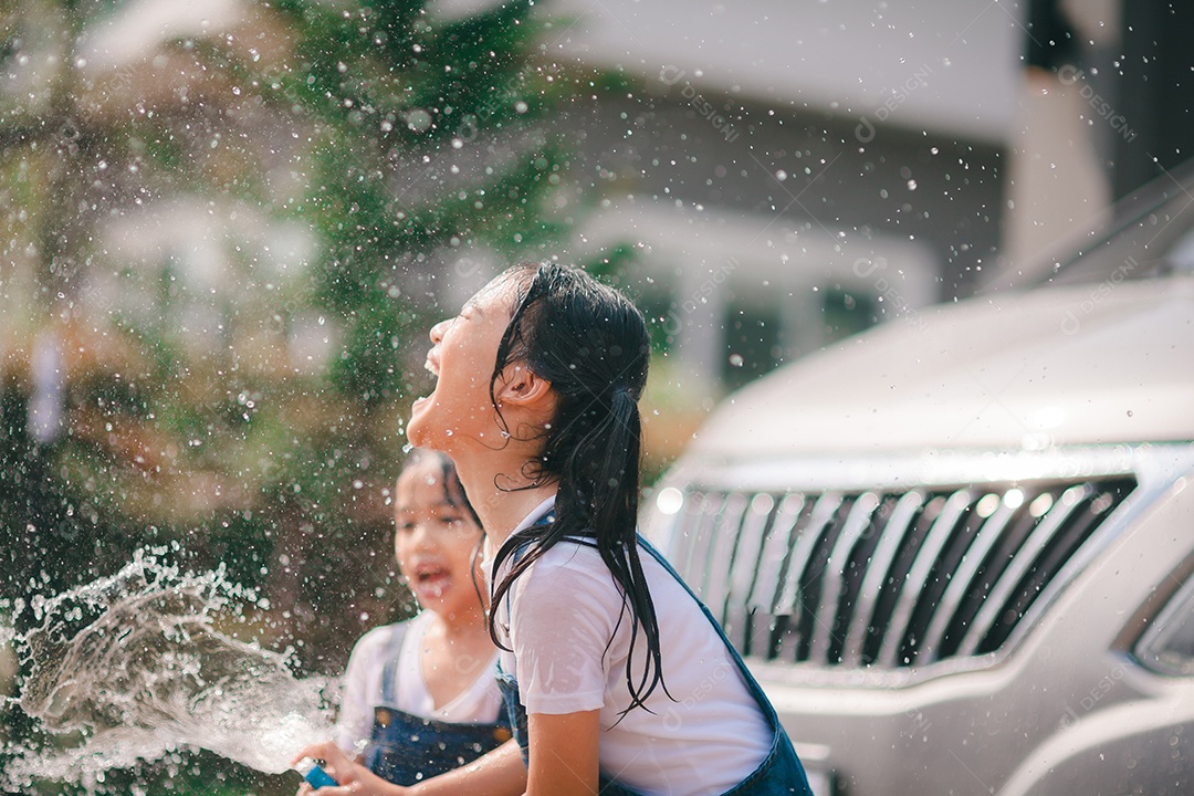 Irmãs asiáticas lavam seus carros e se divertem brincando dentro de casa em um dia quente de verão.
