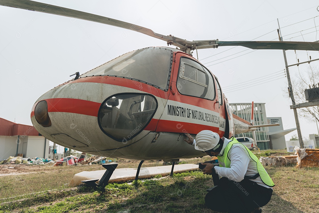 Engenheiro aeronáutico asiático trabalhando em helicóptero em hangar