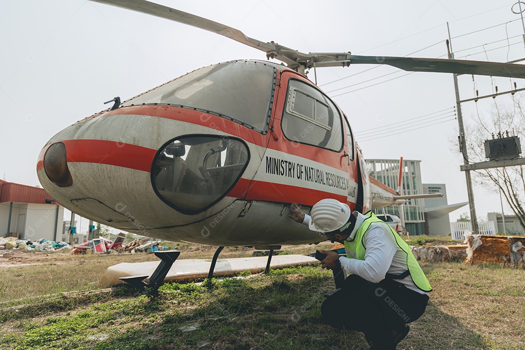 Engenheiro aeronáutico asiático trabalhando em helicóptero em hangar