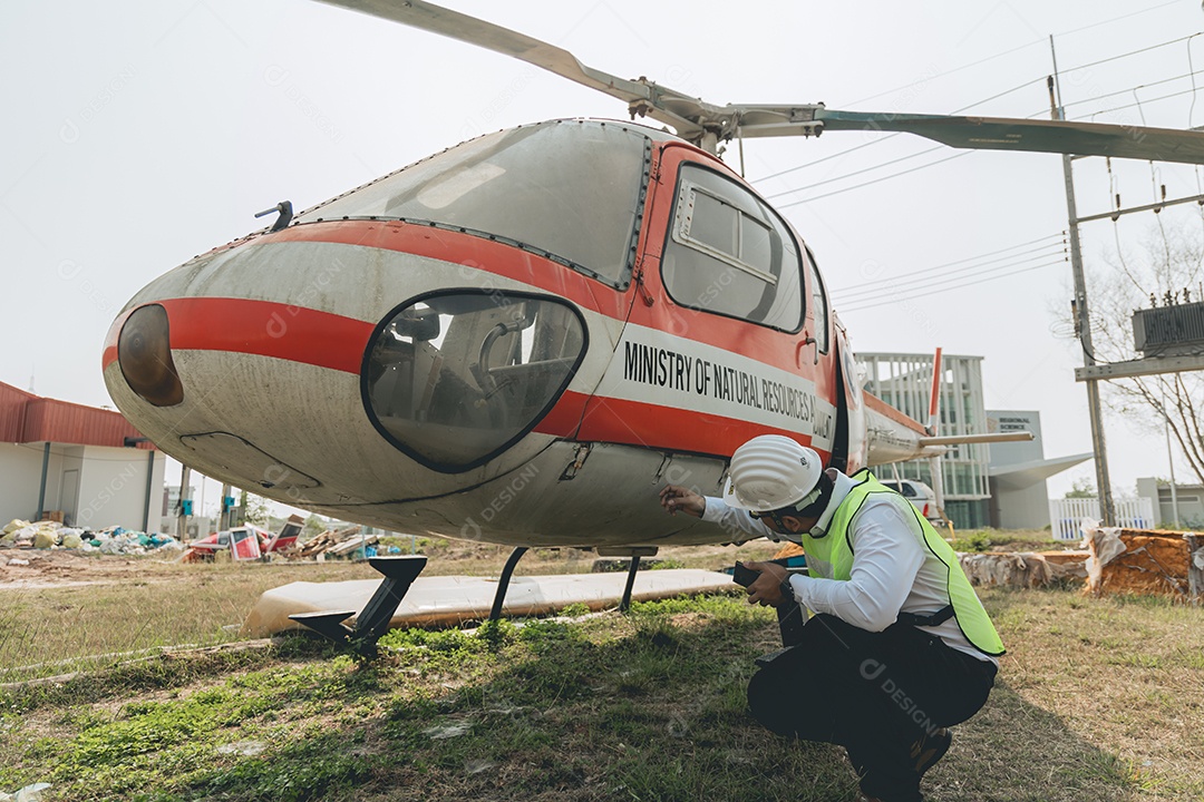 Engenheiro aeronáutico asiático trabalhando em helicóptero em hangar