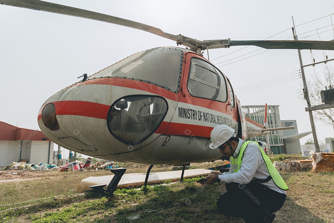 Engenheiro aeronáutico asiático trabalhando em helicóptero em hangar