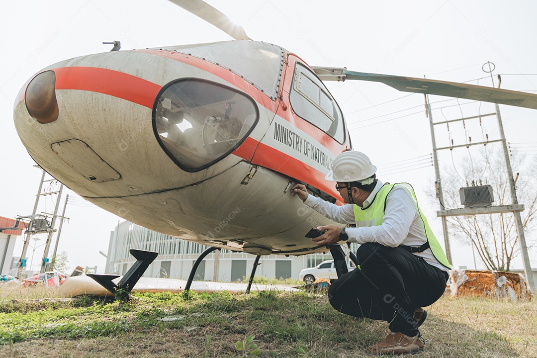 Engenheiro aeronáutico asiático trabalhando em helicóptero em hangar