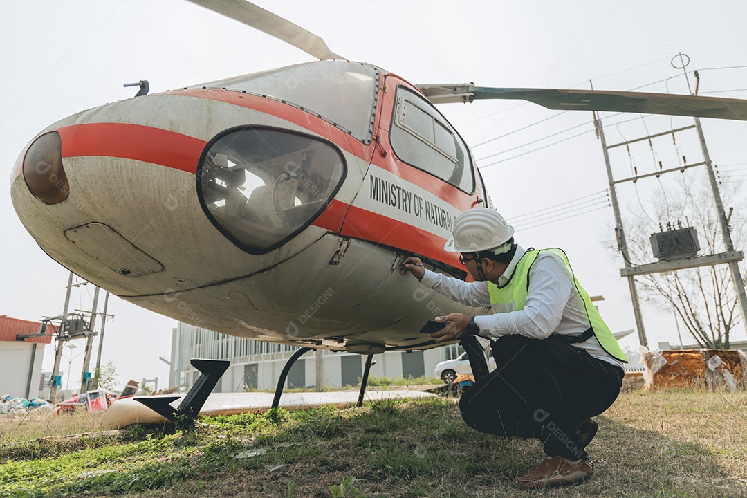 Engenheiro aeronáutico asiático trabalhando em helicóptero em hangar