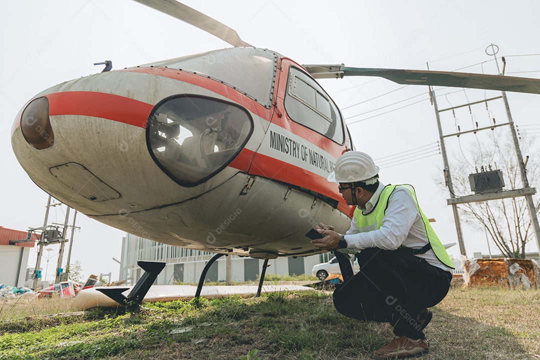 Engenheiro aeronáutico asiático trabalhando em helicóptero em hangar