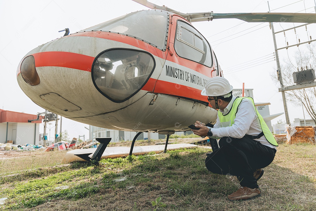 Engenheiro aeronáutico asiático trabalhando em helicóptero em hangar