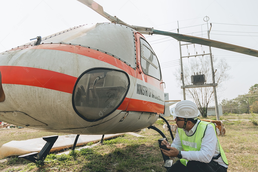 Engenheiro aeronáutico asiático trabalhando em helicóptero em hangar