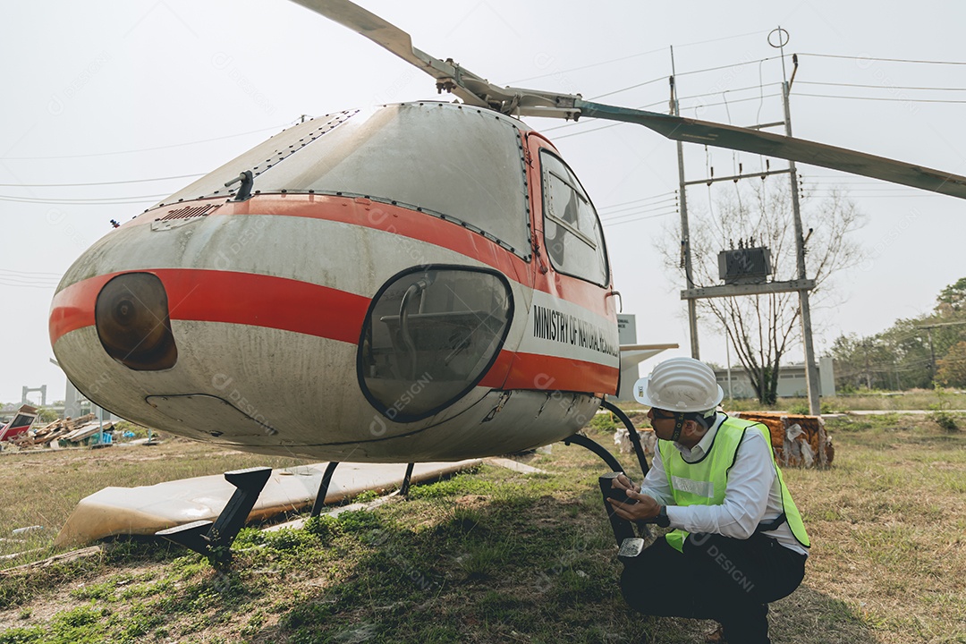 Engenheiro aeronáutico asiático trabalhando em helicóptero em hangar