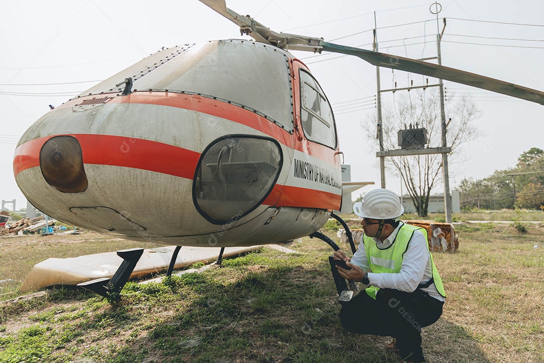 Engenheiro aeronáutico asiático trabalhando em helicóptero em hangar