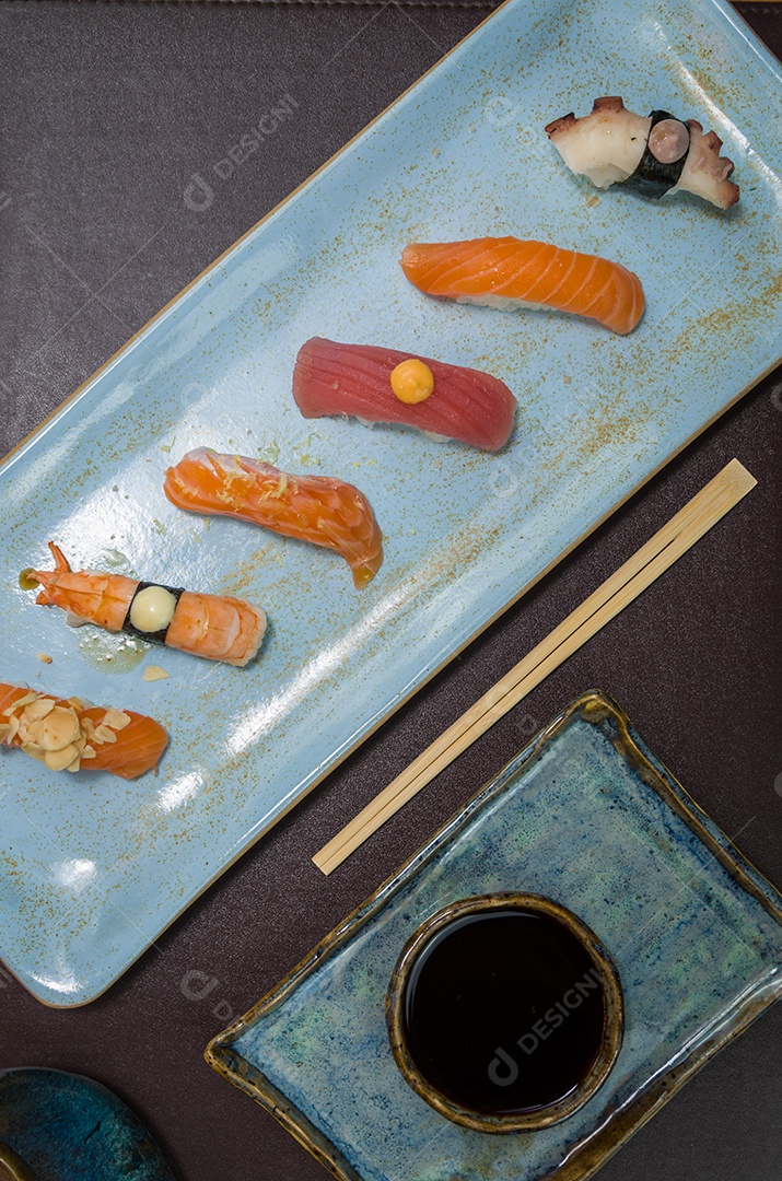 Combinado de diferentes sushis japoneses em um elegante prato azul.