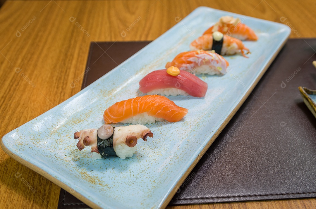 Combinado de diferentes sushis japoneses em um elegante prato azul.