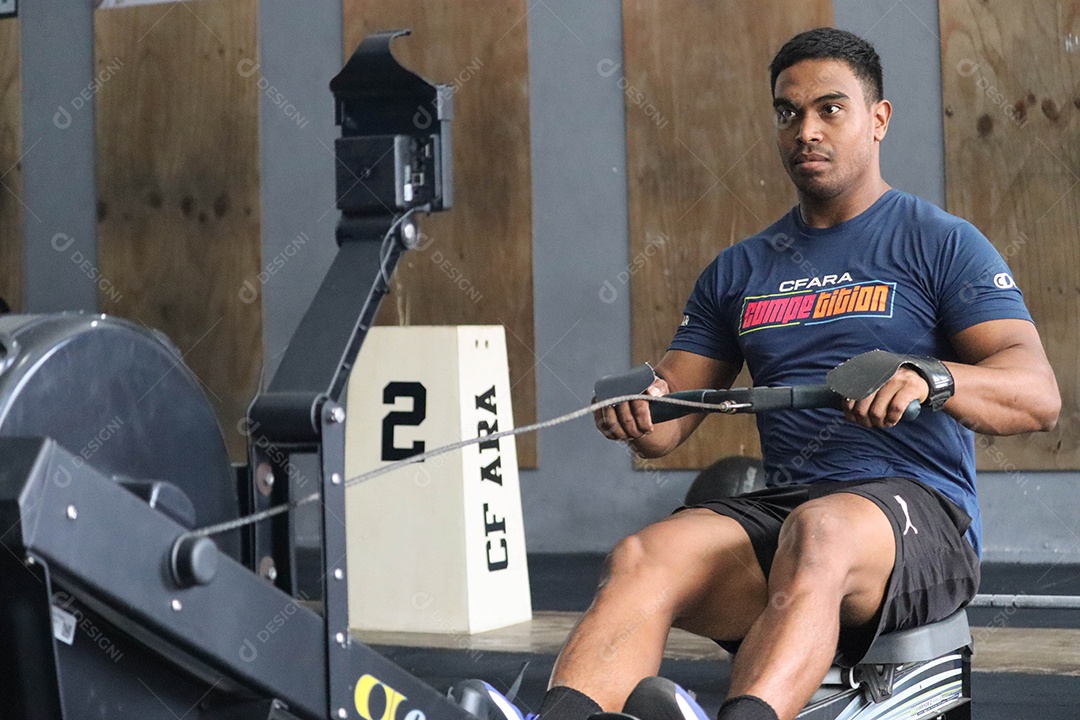 Belo homem moreno fazendo exercício sobre uma academia