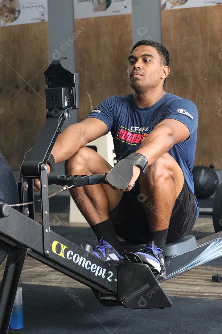 Belo homem moreno fazendo exercício sobre uma academia