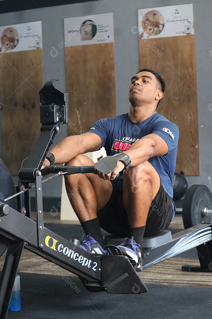 Belo homem moreno fazendo exercício sobre uma academia