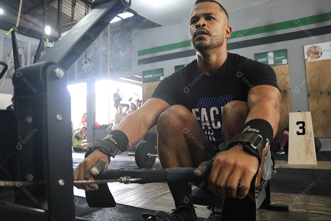 Belo homem moreno fazendo exercício sobre uma academia