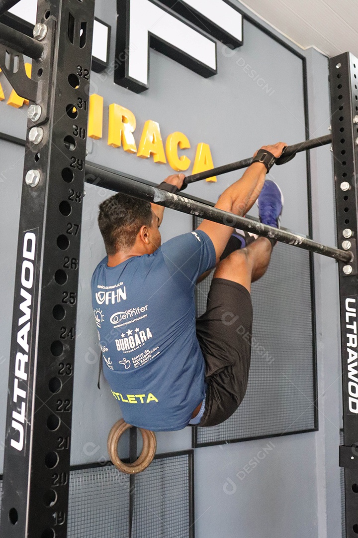Belo homem moreno fazendo exercício em barra sobre uma academia