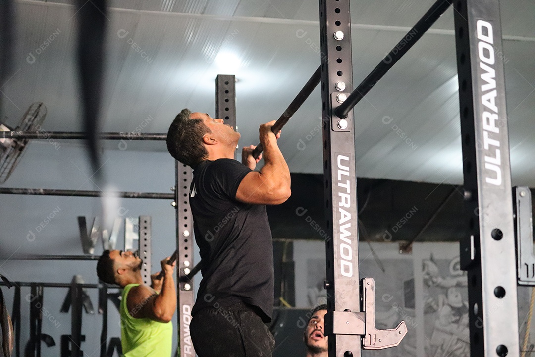 Belos homens fazendo exercício em barra sobre uma academia