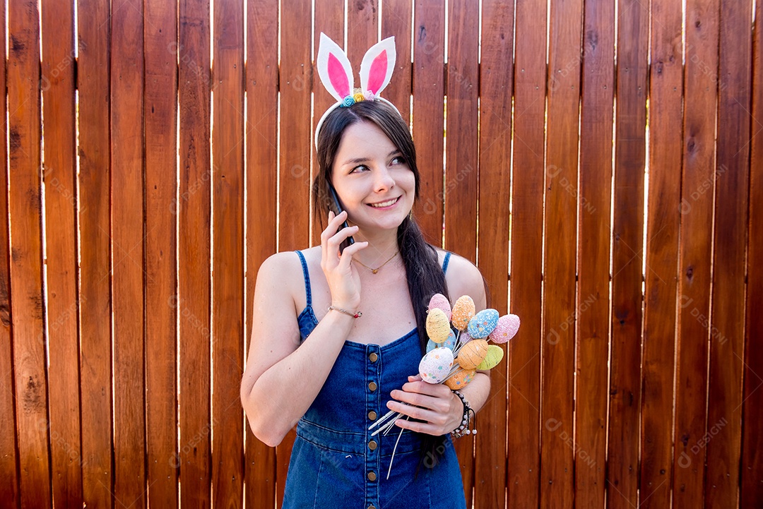 Mulher com orelhas de coelhinho da páscoa mostrando ovos de páscoa