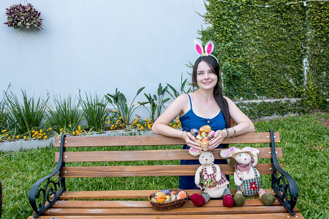 Mulher com orelhas de coelhinho da páscoa mostrando ovos de páscoa