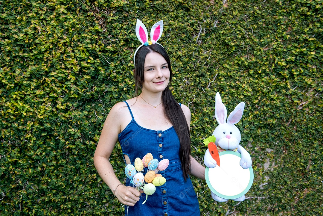 Mulher com orelhas de coelhinho da páscoa mostrando ovos de páscoa