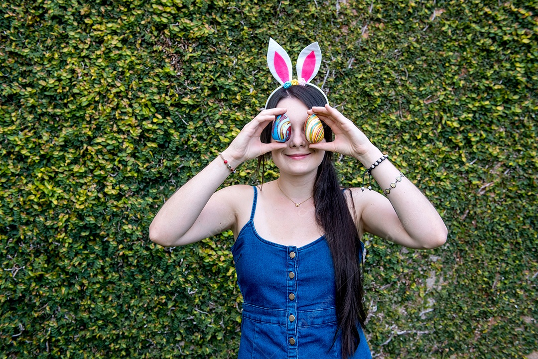 Mulher com orelhas de coelhinho da páscoa mostrando ovos de páscoa