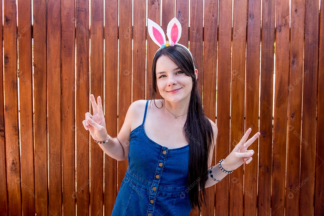 Mulher com orelhas de coelhinho da páscoa mostrando ovos de páscoa
