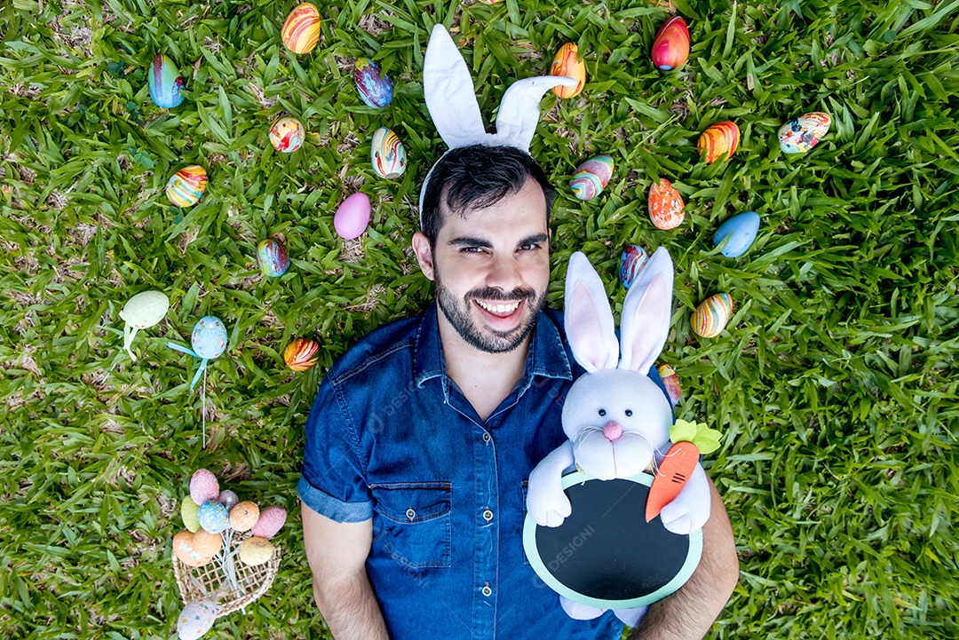 Homem com orelhas de coelhinho da páscoa segurando coelhinho da páscoa