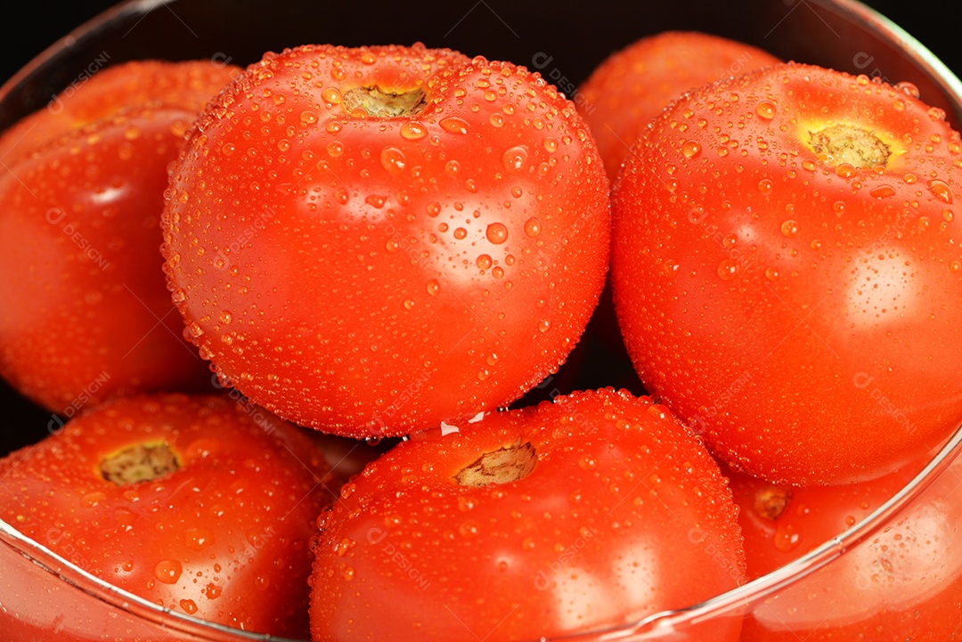 Tomates com gotas de água no fundo preto