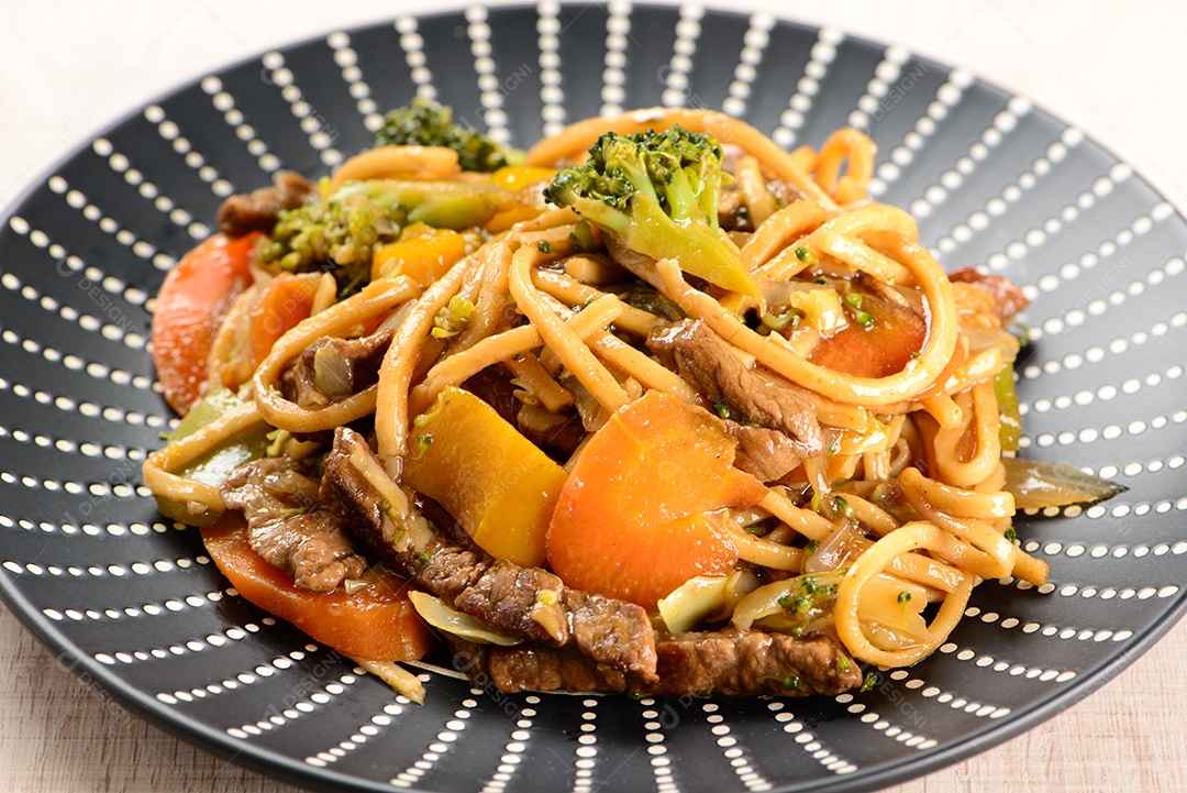 Yakisoba em um prato preto sobre uma mesa