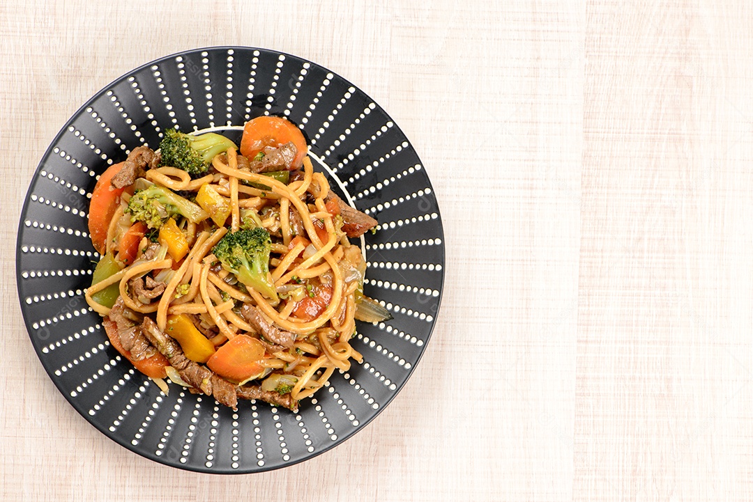 Yakisoba em um prato preto sobre uma mesa