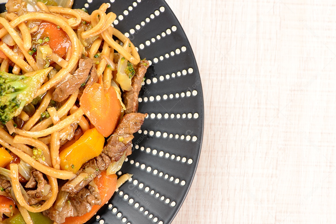 Yakisoba em um prato preto sobre uma mesa