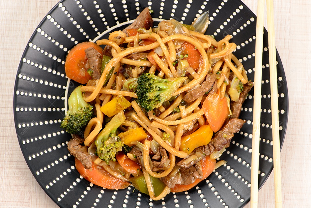 Yakisoba em um prato preto sobre uma mesa