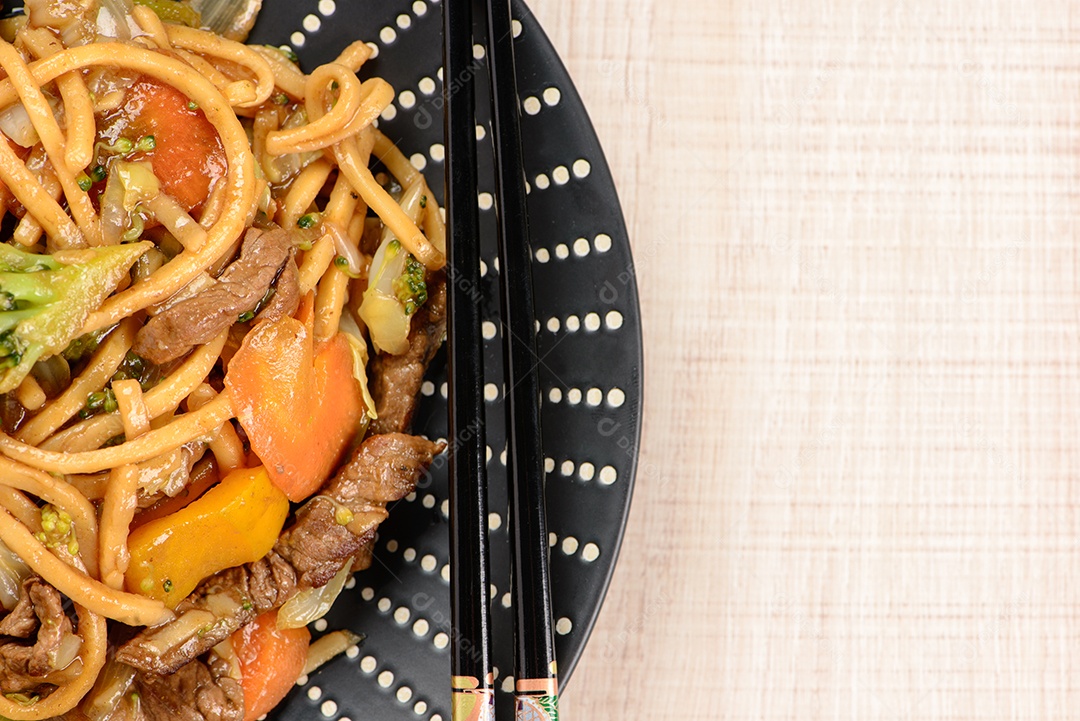 Yakisoba em um prato preto sobre uma mesa