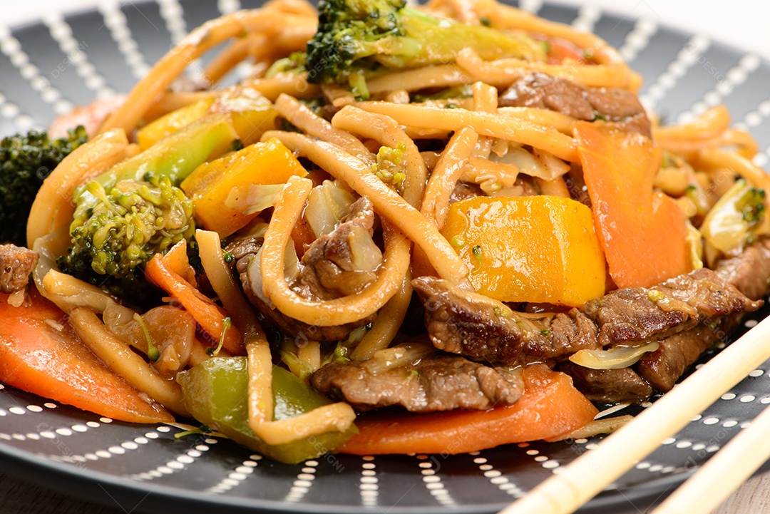 Yakisoba em um prato preto sobre uma mesa